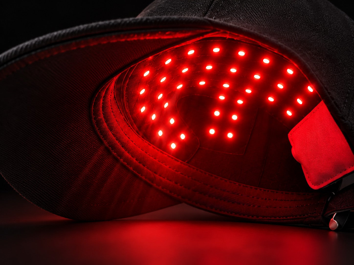 Close-up of the LumaCrown LED light panel glowing red inside the cap